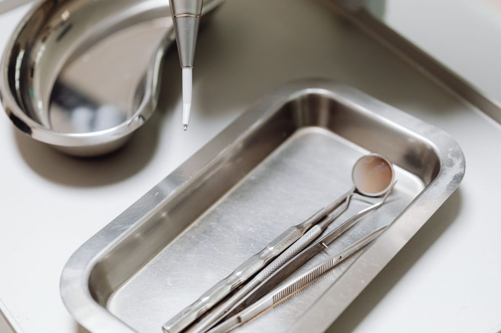 Close-up of dental tools on a clean, sterile metal tray, emphasizing hygiene and precision.