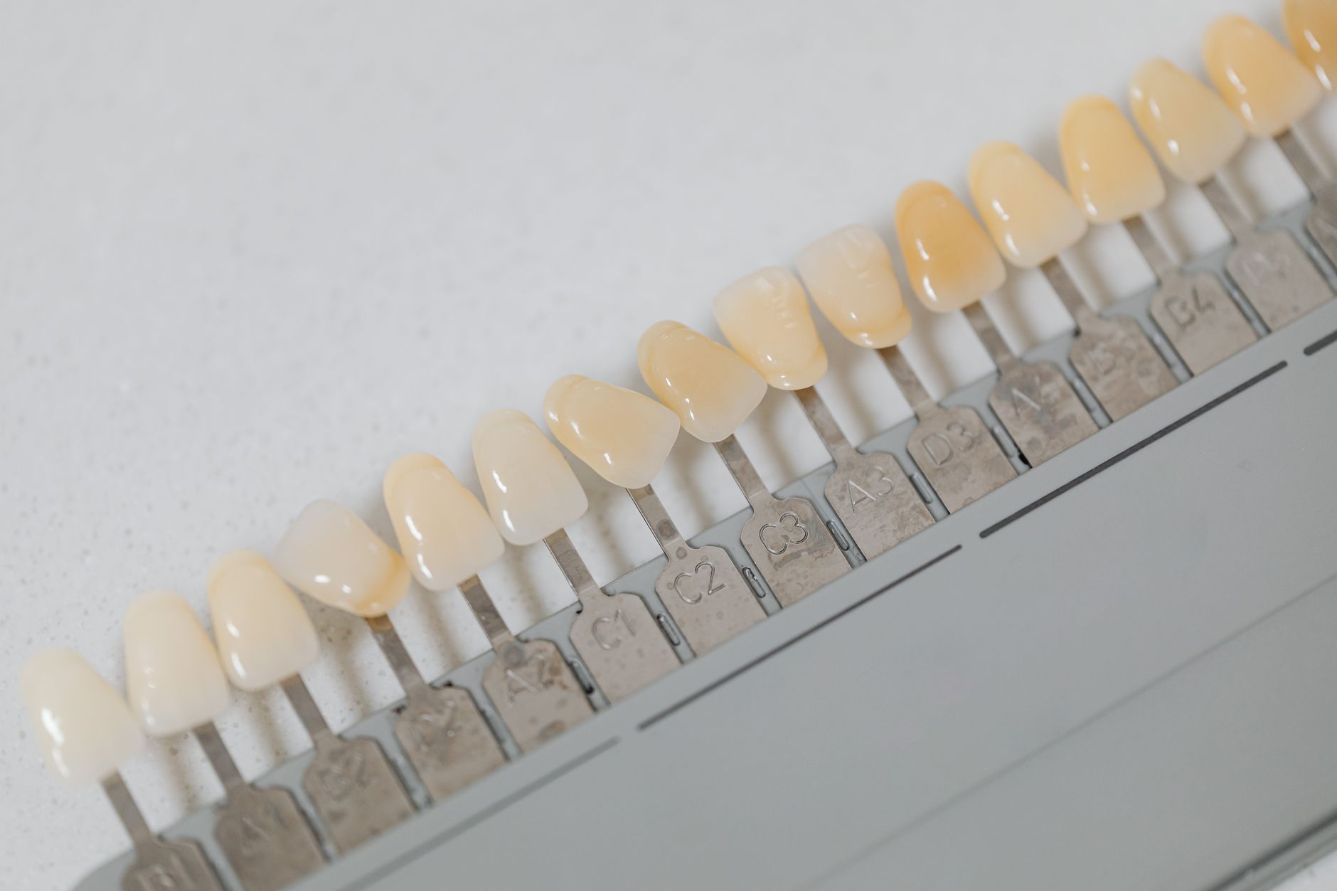 A row of tooth shade tabs on a dental shade guide, from lighter to darker shades